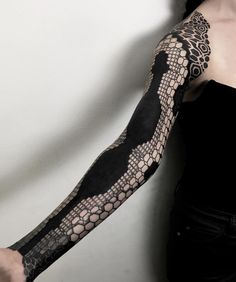 a woman with a black and white tattoo on her arm is posing for the camera