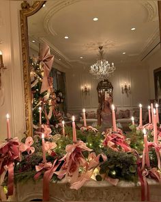 candles are lit in front of a christmas tree with pink ribbons and bows on it