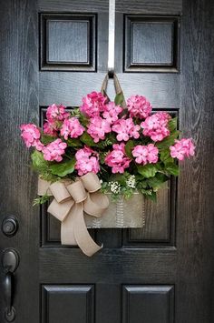 a door with a bow on it and flowers in the pot hanging from the side