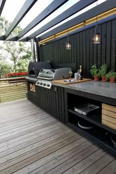 an outdoor kitchen with grill, sink and decking area on the side of a house