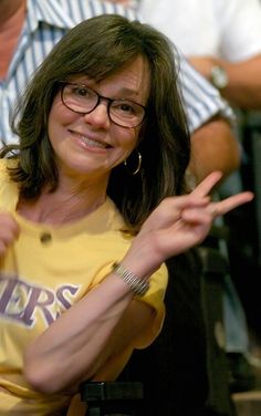 a woman in a yellow shirt is holding her hand out to the side with two other people behind her