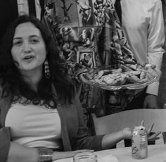 two women sitting at a table with food in front of them and one woman standing behind her