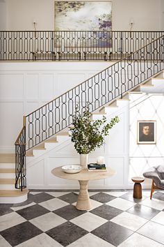 there is a vase with flowers on the table in front of the stair case that leads up to the second floor