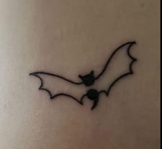 a small bat tattoo on the back of a woman's stomach is shown in black ink