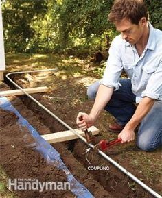 a man kneeling down in the dirt working on some kind of water pipe that is connected to an outlet