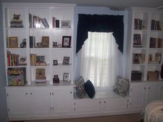 a living room filled with lots of white furniture and bookshelves next to a window