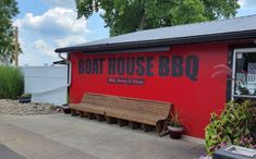 a red boat house bbq with benches and potted plants in the front yard