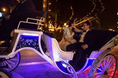 a bride and groom are riding in a horse drawn carriage at night with fairy lights