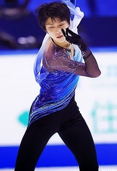 a man is performing on the ice skating rink with his hands up to his face