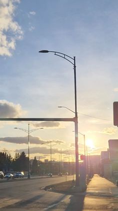 the sun is setting over an intersection with traffic lights and street signs on both sides