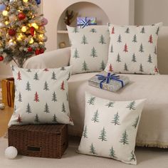 three pillows with christmas trees on them are sitting in front of a christmas tree and presents