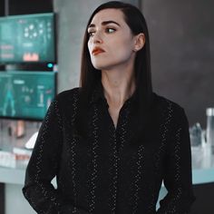 a woman standing in front of a computer monitor with her hands on her hips and looking up