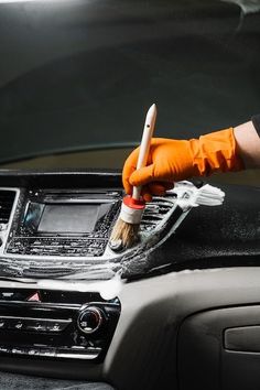 a person in an orange glove is cleaning the interior of a car with a brush