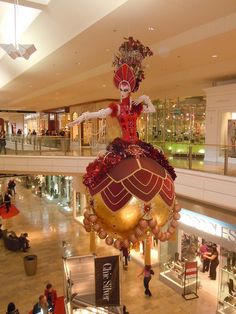 an elaborately decorated christmas ornament hangs from the ceiling in a shopping mall