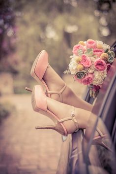 a bouquet of flowers sitting on the side of a car with high heeled shoes