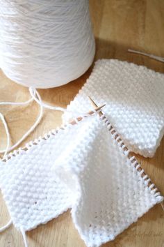 two pieces of white yarn sitting on top of a wooden table