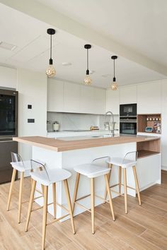 a kitchen with two stools and an island in the middle of it, surrounded by wooden flooring