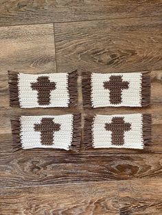 three crocheted squares with brown and white crosses on them sitting on a wood floor