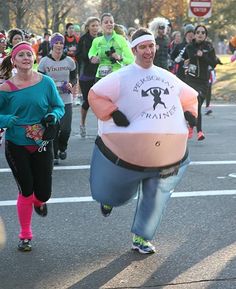 a group of people that are running in the street with some balloons on their backs