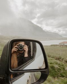 a woman taking a photo in the side mirror of a car