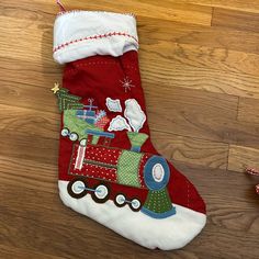 a red christmas stocking with a train on it sitting on a wooden floor next to candy canes