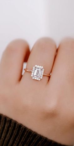 a woman's hand holding an engagement ring with a diamond in the middle and a baguette setting on it