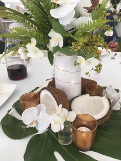 the table is set with white flowers and coconuts, candles, and other items