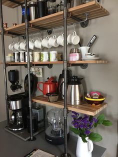 a shelf with coffee cups and other items on it in a home kitchen area,