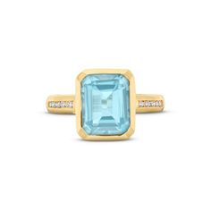 This Blue Topaz Diamond Bezel Ring features an emerald cut blue topaz totaling approximately 4 carats, accented by a line of brilliant round diamonds on each side. Yellow Gold Blue Topaz Baguette Cut Ring, Blue Topaz Ring With Emerald Cut And Bezel Setting, Yellow Gold Baguette Cut Blue Topaz Ring, Blue Topaz Baguette Cut Ring In Yellow Gold, Baguette Cut Blue Topaz Ring In Yellow Gold, Emerald Cut Topaz Ring With Diamond And Gemstone Accents, Emerald Cut Topaz Ring With Gemstone Accents, Luxury Baguette-cut Topaz Ring, Emerald-cut Blue Topaz Ring With Accent Stones