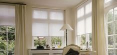 a living room filled with white furniture and lots of window coverings on the windowsill