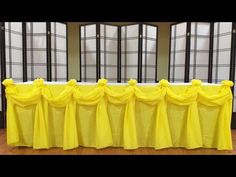 a long table with yellow cloths on it and windows in the backround