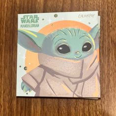 a card with an image of the child yoda from star wars, on top of a wooden table