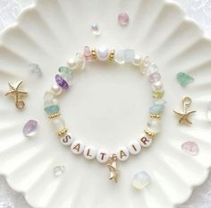 a white plate topped with a bracelet filled with beads and charms on top of it