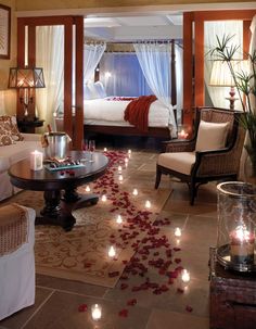 a bedroom with candles on the floor and rose petals all over the floor in front of it