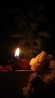 a lit candle sitting on top of a table next to flowers