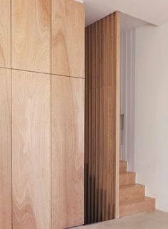 an empty room with wood paneling on the wall and stairs leading up to it