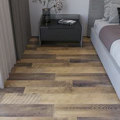 a bed sitting next to a nightstand on top of a wooden floor