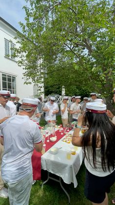 a group of people dressed in sailor hats are eating at a picnic table outside on the grass