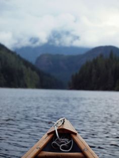 the bow of a canoe on a lake with mountains in the background