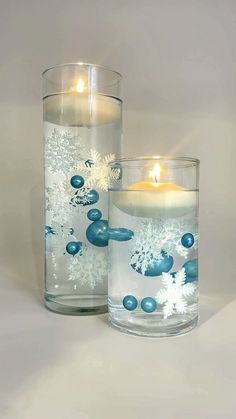 two glass vases filled with water and lit candles