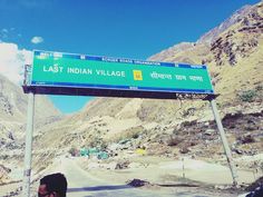 a woman standing in front of a road sign on the side of a mountain range