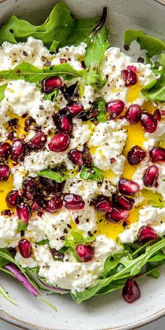 a salad with feta cheese and pomegranates in a white bowl