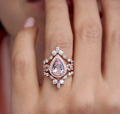 a woman's hand with a pink diamond ring on it