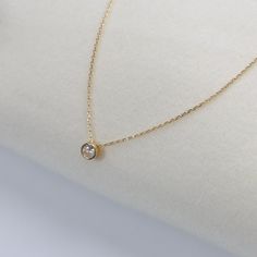 Embrace understated elegance with our 18k Gold Filled Solitaire CZ Necklace. This charming piece features a brilliant 6.5mm round cut cubic zirconia stone, securely set in a bezel setting that enhances its sparkle. The solitaire pendant hangs gracefully from a delicate 16-inch link chain, complemented by a 2-inch extender for adjustable length. DETAILS: * 18k gold-filled, Water resistant, Cubic zirconia AAAAA MEASUREMENTS: * Charm Size: 6.5mm * Size: 16" long + 2 inches extender chain CARING TIPS: * Avoid contact with sweat, lotions & perfumes as these can tarnish the jewelry * Keep jewelry clean and dry    * We recommend using polishing cloths to restore the shine to your jewelry OTHER INFORMATION: * All items are packaged in elegant jewelry pouches  * Have any questions? Feel free to con Minimalist Round Birthstone Necklace For Formal Events, Minimalist Ethical Solitaire Necklace With Round Stone, Minimalist Round Diamond Birthstone Necklace, Minimalist Solitaire Birthstone Necklace, Minimalist Round Birthstone Necklace With Single Diamond, Minimalist Round Cut Birthstone Necklace For Formal Occasions, Minimalist Formal Birthstone Necklace With Delicate Chain, Minimalist Diamond Necklace With Bezel Setting, Minimalist Bezel Setting Birthstone Necklace