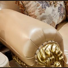 a close up of a couch with pillows on the back and gold trimmings