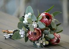 a bouquet of flowers sitting on top of a wooden table covered in leaves and buds