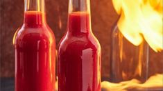 two bottles filled with red liquid sitting on top of a table next to a fire