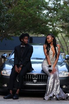 two people sitting on the hood of a car