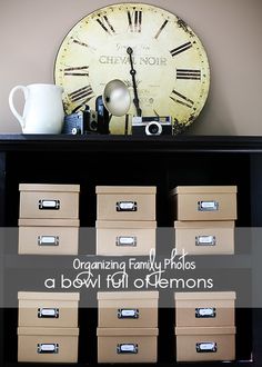 an old clock sits on top of a bookcase with many boxes in front of it