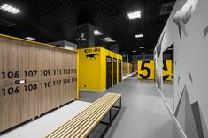 an empty room with wooden benches and yellow partitions on the walls that have numbers painted on them